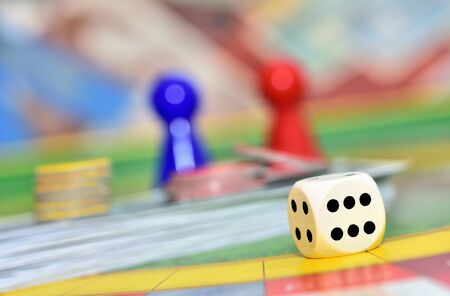 Dice and red and blue figures in background on the board.の写真素材