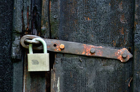Old historical latch on wooden door and padlock.