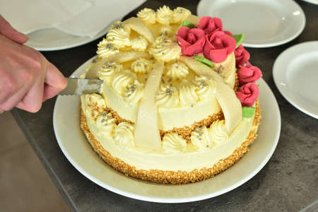Slicing a beautifully decorated wedding cake covered with marzipan ornaments
