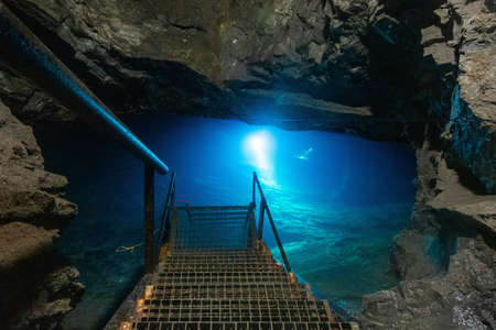 Cave divers training deep cave dives in old coal mine lake. Light from cold blue waterの写真素材