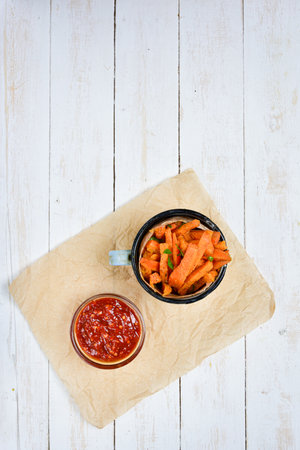 View from above of a mug full of healthy sweet potato fries and hot chili dip.