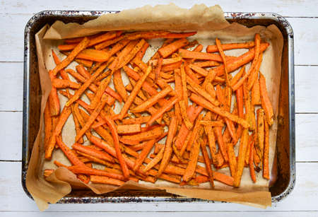 Homemade sweet potatoes chips on baking paper in an old baking tray. Top view. Vegetarian - vegan...