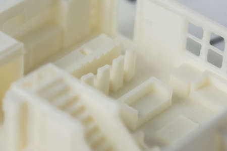 Close-up of 3D model of the house floor with staircase and furniture printed on a 3D printer with white filament by FDM technology.の写真素材