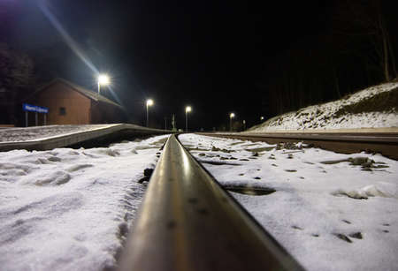 View directly from the train tracks on a snowy railway station at night
