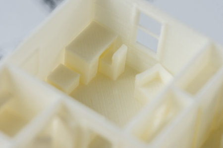 Macro detail of architectural 3D model of the house interior with furniture and big kitchen table printed on a 3D printer with white filament by FDM technology.の写真素材