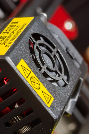 Close-up of 3D printer printerhead with hotend and fan. Modern 3D printer detail. Vertical photo.