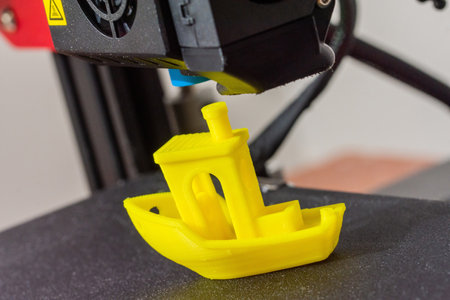 Finished 3D printed model of yellow PLA ship. Detail of printhead with fan and hotend.の写真素材