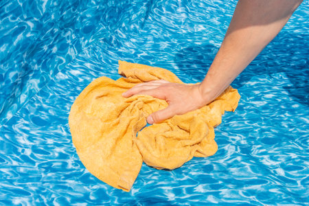 Cose-up on a hand with a rag when cleaning a garden pool. Preparation for the summer season.の写真素材