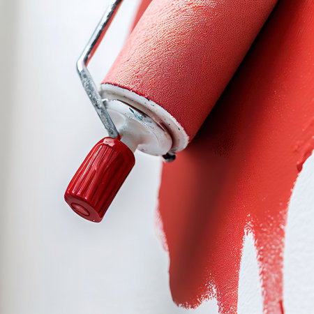 Close up of Roller painting a white wall with red paintの素材