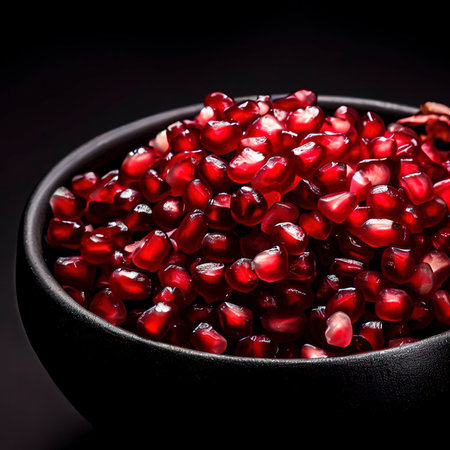 Pomegranate seeds in a black bowl on a black backgroundの素材