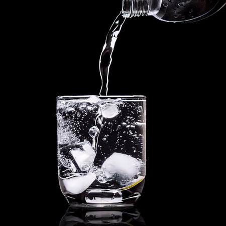 Pouring gin tonic drink into a glass on black backgroundの素材