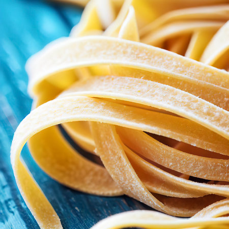 Close up of a raw dry italian pasta fettuccine on blue wooden tableの素材