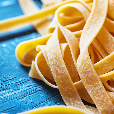 Close up of a raw dry italian pasta fettuccine on blue wooden tableの素材