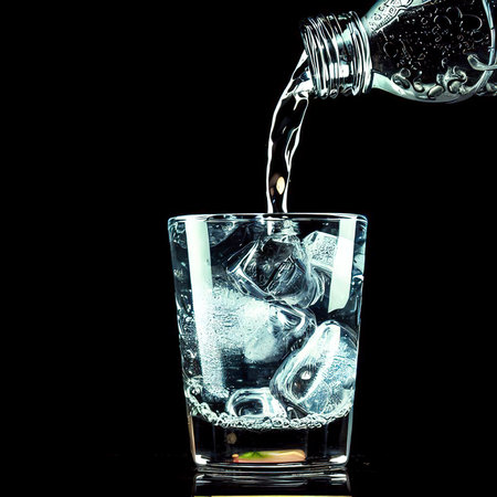 Pouring gin tonic drink into a glass on black backgroundの素材
