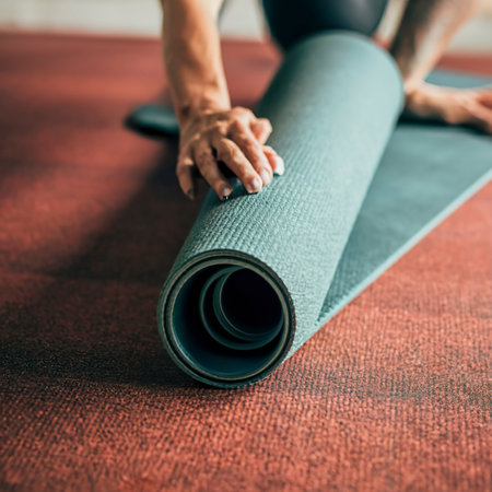 Exercise mat rolling keeping after yoga class. Workout and sport training concept. Hands on carpetの素材