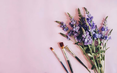 Purple flowers and paint brush on pink background. Flat lay.の素材