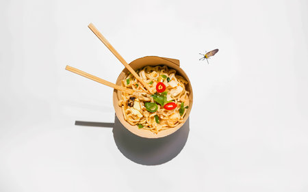 Chinese noodles in a cardboard bowl on a white backgroundの素材