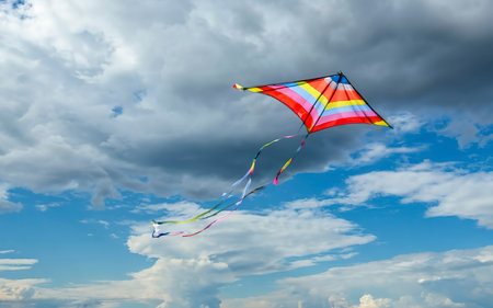 rainbow kite flying in blue sky with clouds in summer with copyspaceの素材