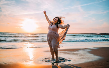 Beautiful young woman in long dress on the beach at sunset.の素材