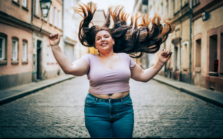 Portrait of happy young woman with flying hair on the city streetの素材