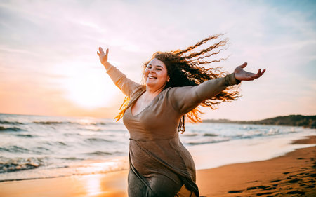Beautiful happy young woman having fun on the beach at sunset.の素材