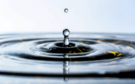 Closeup of water drops sliding on light wet surface. White backgroundの素材