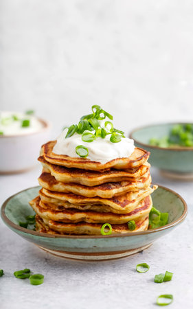 potato pancakes with yogurt and green onions and black pepper. in clay pots on a white backgroundの素材