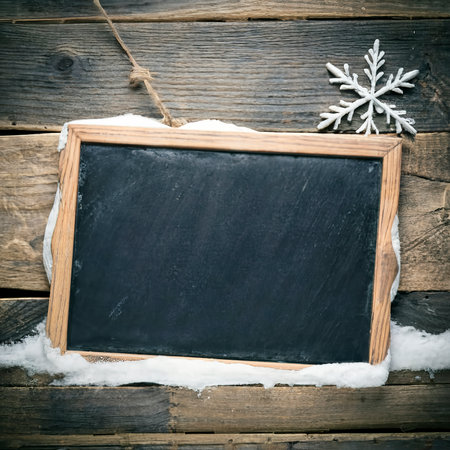 Black board of slate on old rustic wooden background, with snowの素材