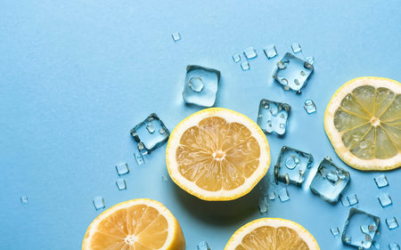 juicy fresh yellow lemon slices and ice cubes on a blue background.の素材