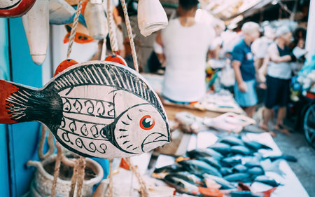 Handmade colored wooden toy in the form of fish for sale at street souvenir marketの素材