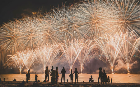 Fireworks with silhouettes of people in a holiday events. New Year fireworks on the beachの素材