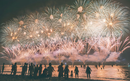 Fireworks with silhouettes of people in a holiday events. New Year fireworks on the beachの素材