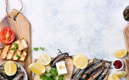 Fried anchovies served with lemon, tomatoes, olives and grilled halloumi cheese over white backgroundの素材