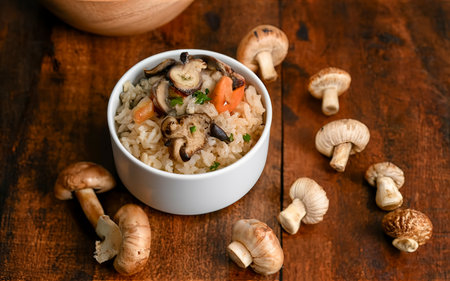 cooked rice with dried forest mushrooms, in a bowl on a wooden tableの素材