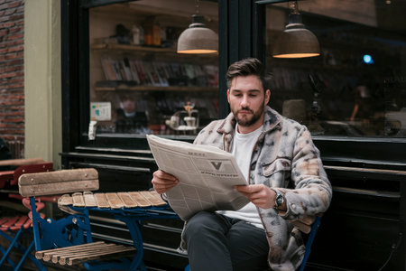 a men reads a newspaper outside a cafeの素材