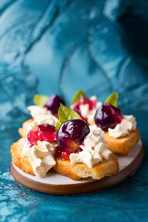 Crostini, bruschetta with plum, berry marmalade and goat cheese on a blue turquoise blue backgroundの素材