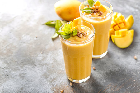 Refreshing and healthy mango smoothie in tall glassesの写真素材