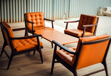 Four vintage orange upholstered chairs with wooden frames are arranged around a rectangular wooden table, creating a retro seating area.の写真素材