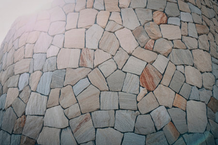 A close-up view of a wall constructed with irregularly shaped natural stones, showcasing a rustic and textured surface with varying shades of grey and beige.の写真素材