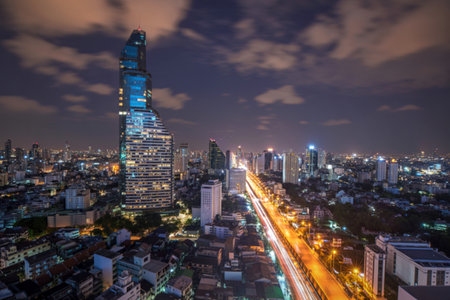 A vibrant city skyline at dusk, featuring towering illuminated skyscrapers and a brightly lit highway with streaks of car lights.の写真素材
