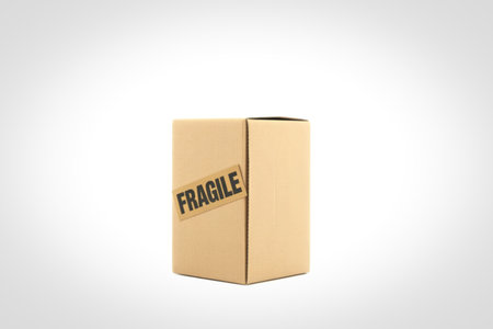 A closed cardboard box with the word "FRAGILE" printed diagonally on its side, isolated on a plain white background.の写真素材