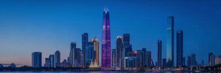 The majestic Burj Khalifa glows with purple light against a twilight sky, surrounded by other...