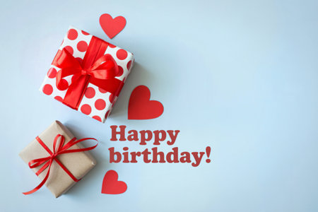 Two beautifully wrapped birthday gifts adorned with red ribbons and surrounded by decorative red hearts, with a "Happy Birthday" message.の写真素材