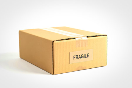 A closed brown cardboard shipping box with a white 'FRAGILE' label and clear tape on a white background.の写真素材