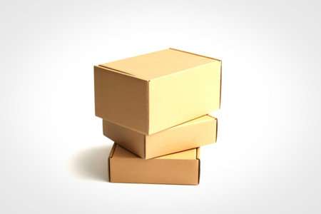 A small stack of three brown cardboard boxes are neatly arranged on a clean white surface, casting a subtle shadow.の写真素材