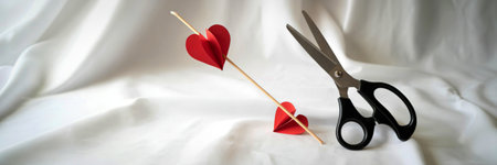 A pair of black scissors poised to cut a small red heart attached to a thin stick, set against a...