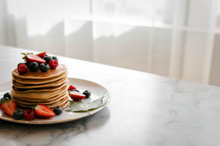 A tall stack of golden brown pancakes adorned with fresh strawberries, blueberries, and raspberries...