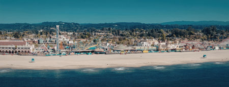 A scenic view of a beach with a town in the background, featuring a sandy shore, calm waters, and a...