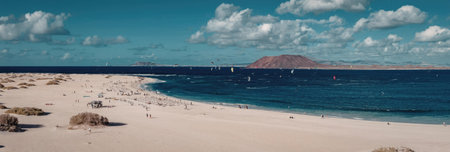 A serene sandy beach with a vast ocean view, featuring a mountain in the distance under a blue sky...