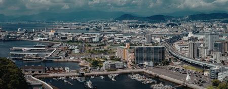 An aerial view of a coastal city with a large body of water, boats, and a mountain range in the...
